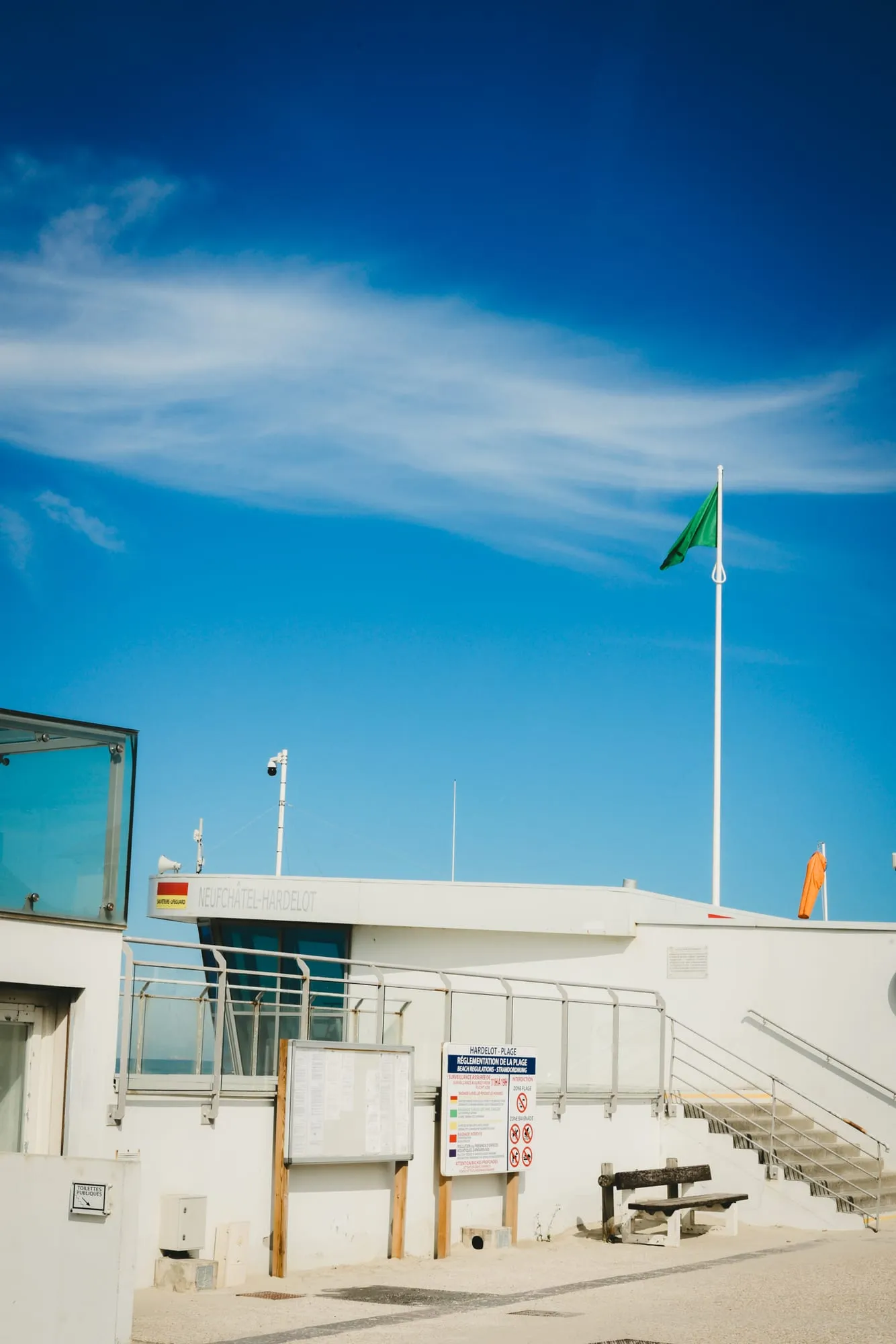 Le poste de secours blanc d’Hardelot et son drapeau vert sous un grand ciel bleu.
