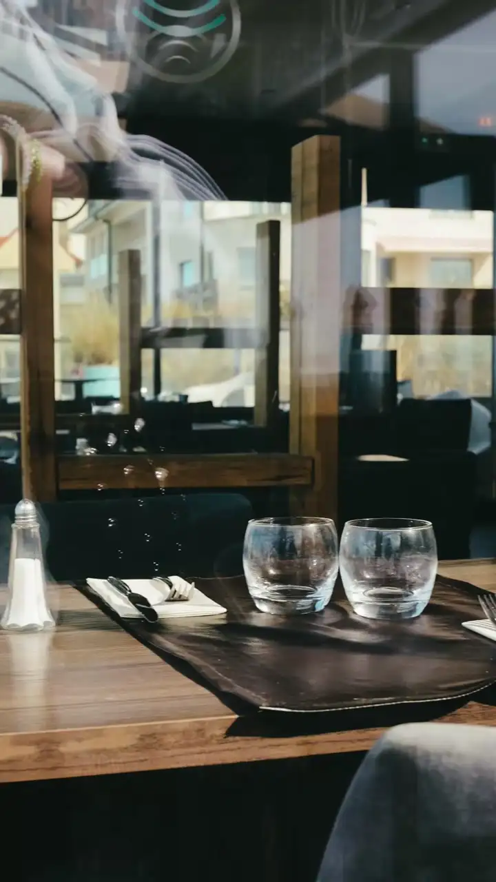 Une table dressée dans la salle de L’Océan : deux verres, des couverts, la lumière de la plage derrière la vitre.